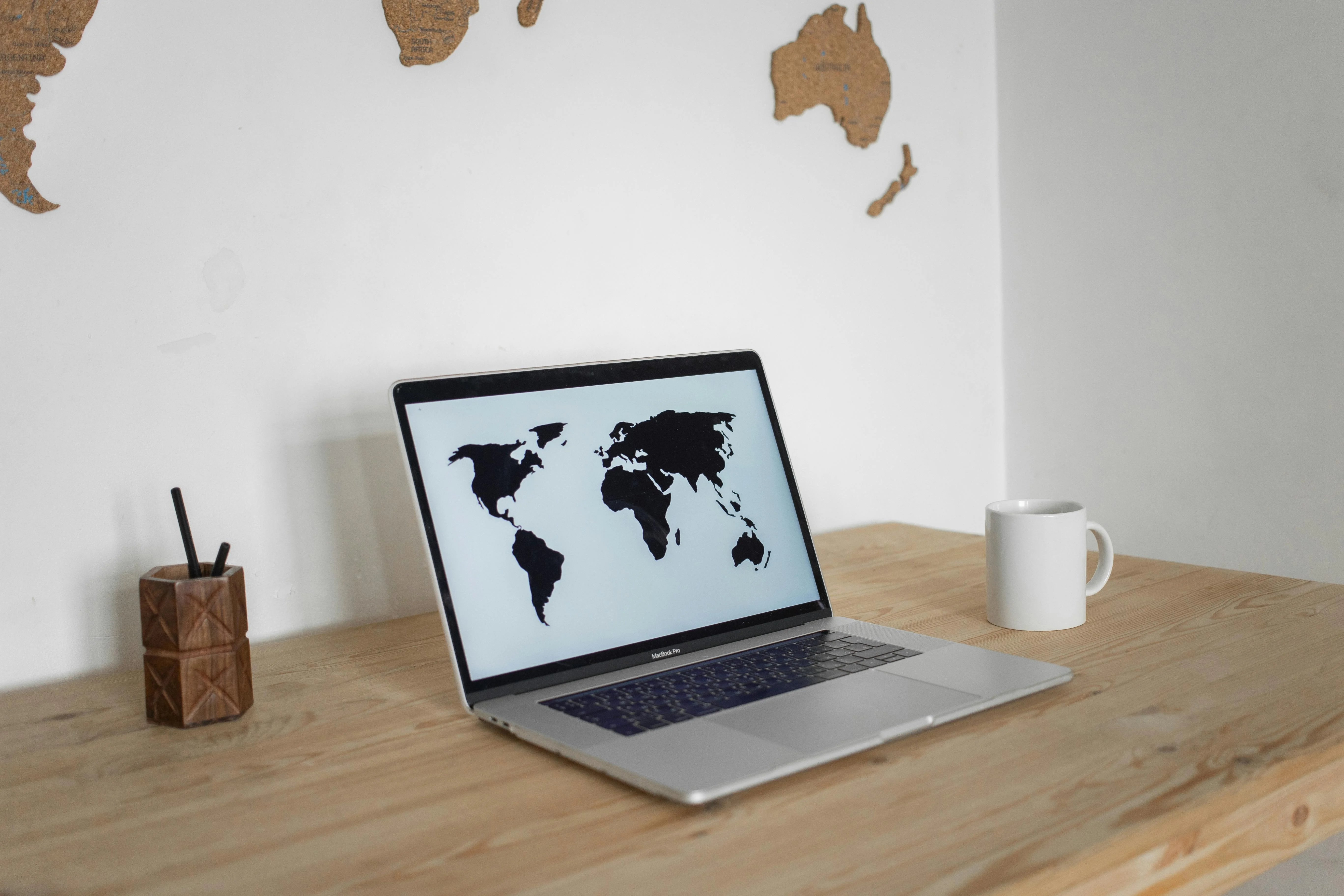 Agent typing on laptop with MLS map on screen, coffee cup nearby